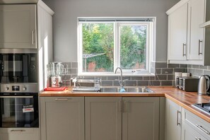 A modern kitchen with a built-in oven, a blender, a toaster, and a window with a view of greenery.