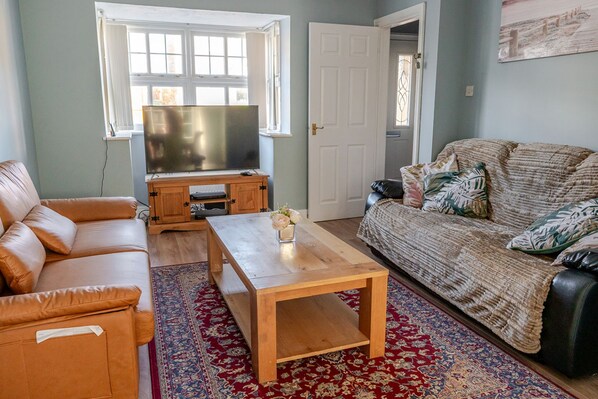 A living room with a sofa, a coffee table, a television, and a patterned rug.