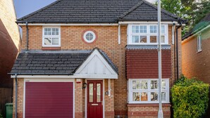 Ein zweistöckiges Wohnhaus mit roter Garage, Eingangstür und kleiner Veranda.