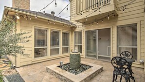 Un patio con una chimenea de piedra, asientos exteriores y luces colgantes.