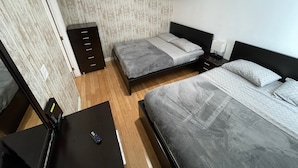Ein Schlafzimmer mit zwei Betten, einem Schminktisch, einem Nachttisch und einem Wandbild.