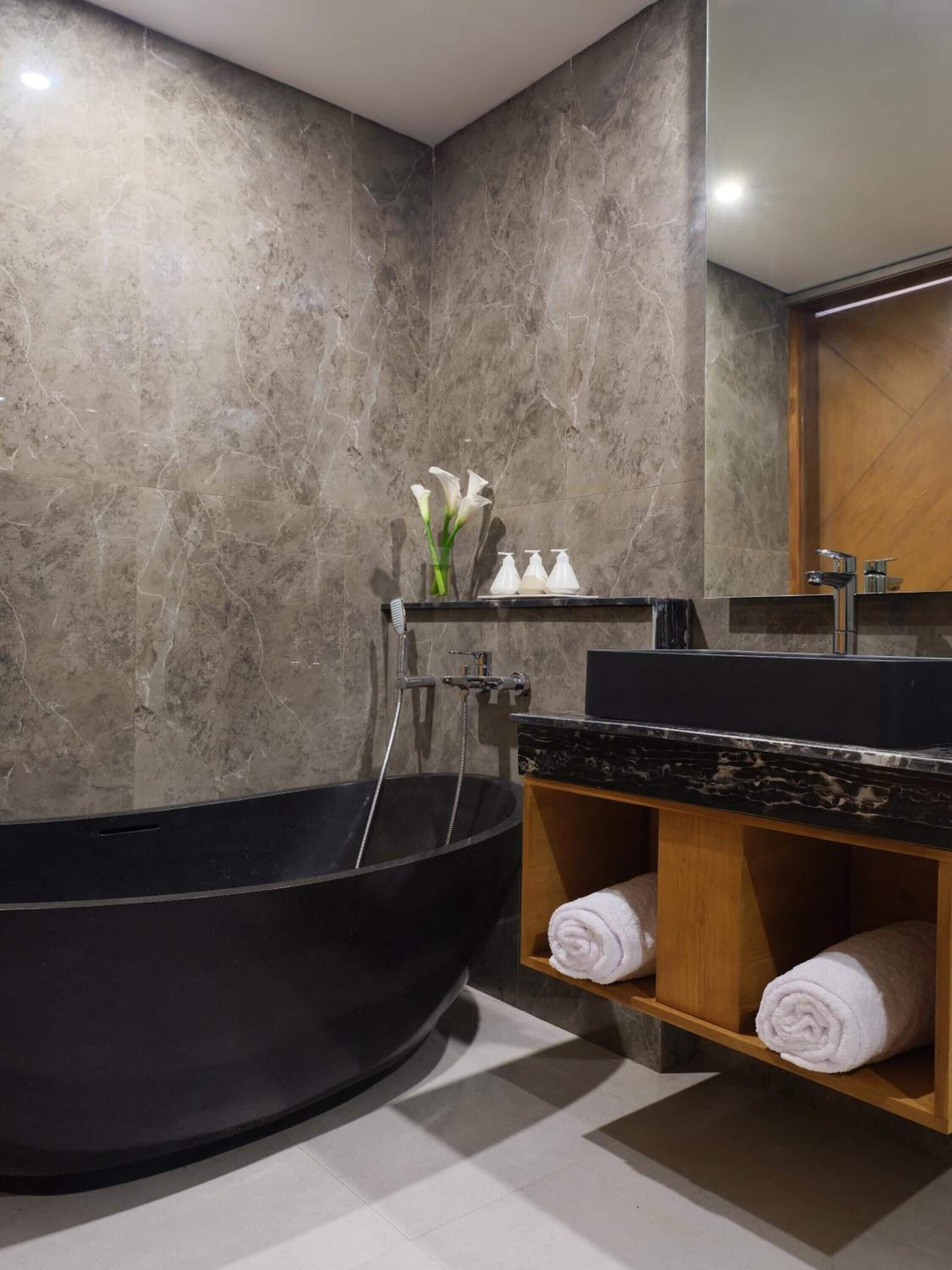 A modern bathroom with a freestanding bathtub, a wooden vanity with a black countertop, and a mirror above the sink.