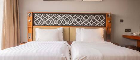 Cama de casal com cabeceira estampada, duas mesas de cabeceira e telefone fixado na parede.