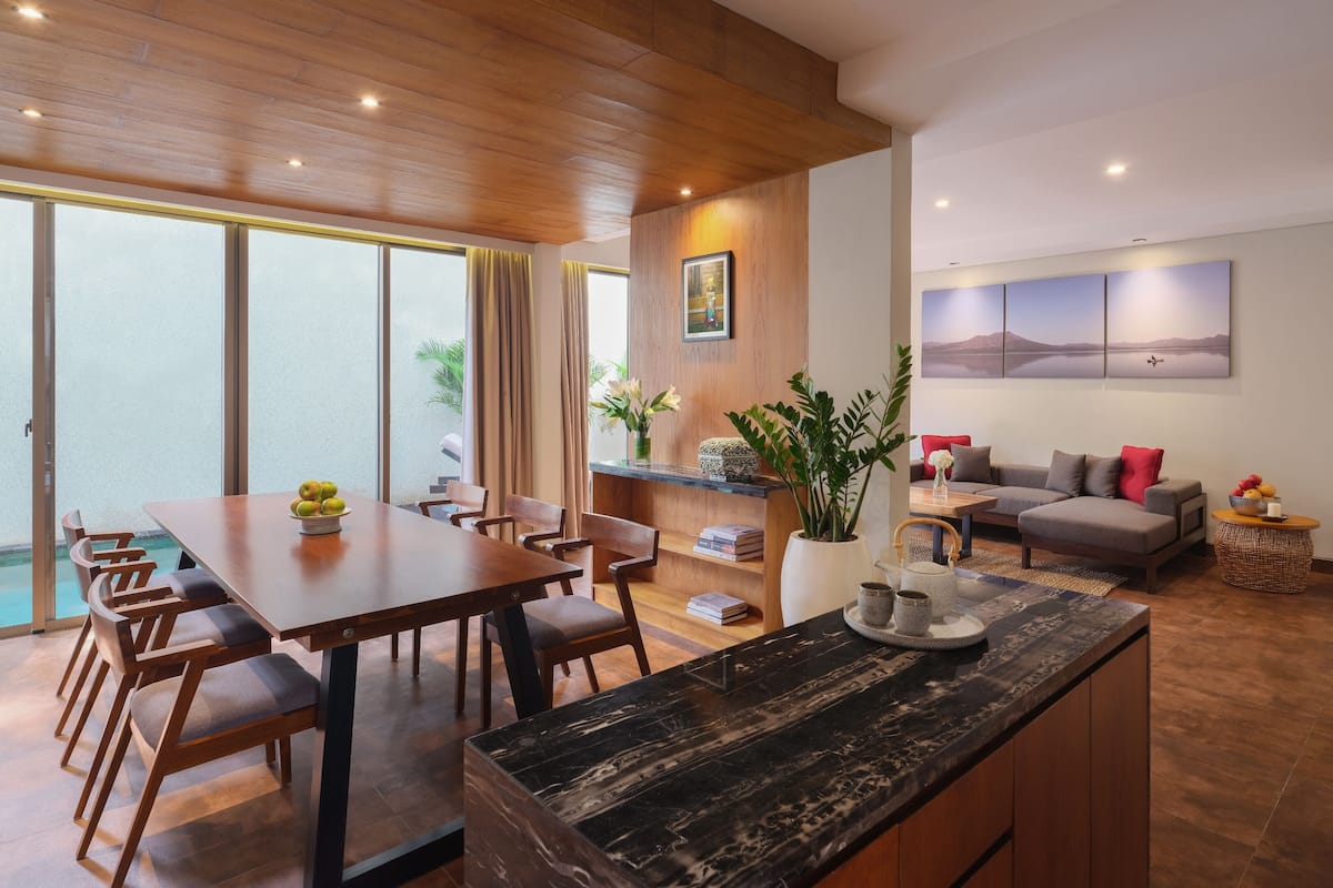 A modern living room with a dining area, wooden ceiling, and large windows.