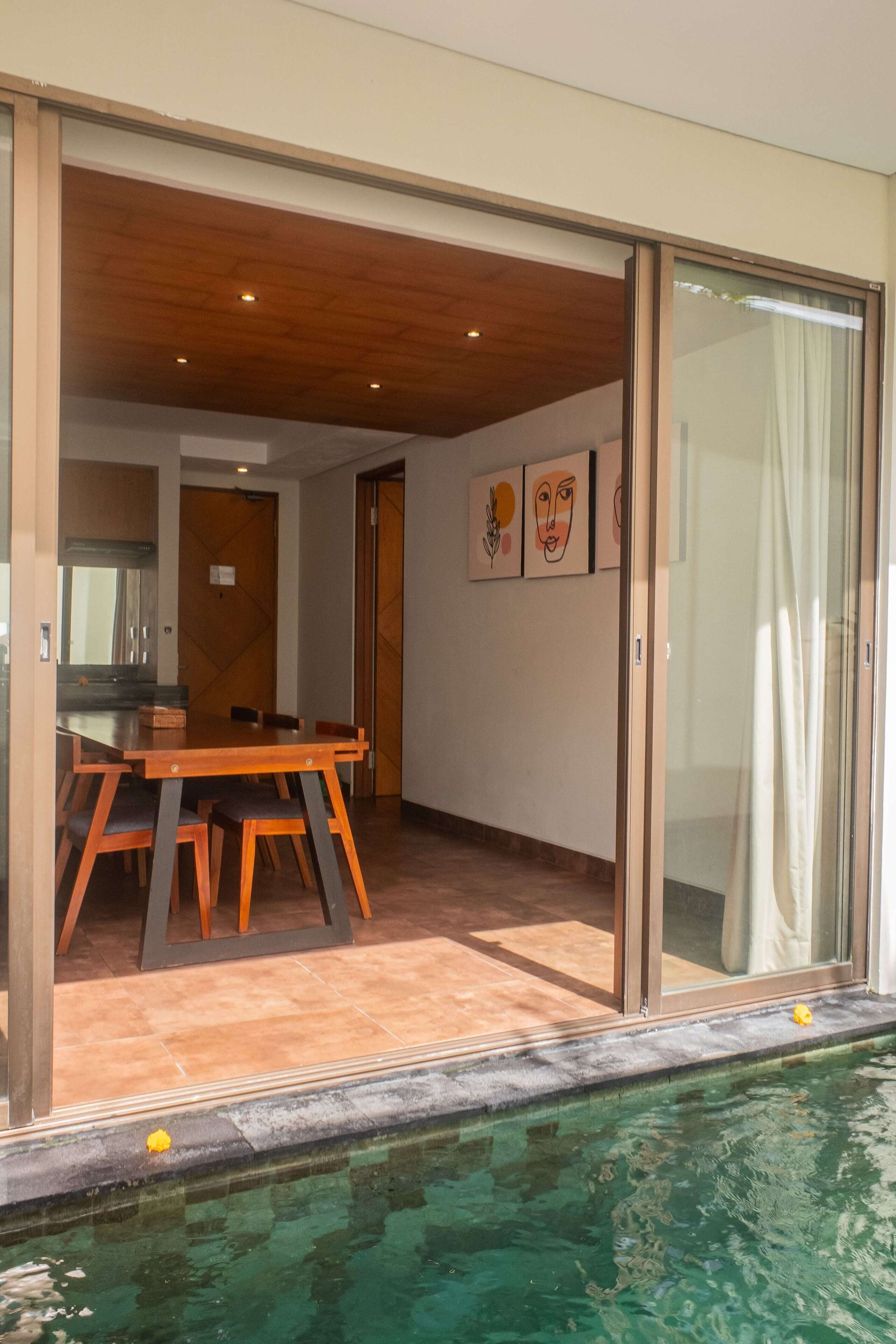 A modern interior with a dining area, a kitchen, and a glass door leading to a pool.