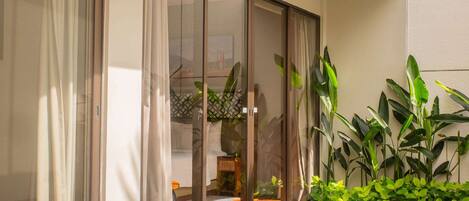 Un área de piscina interior moderna con puertas de vidrio que dan a un salón, rodeada de abundante vegetación.