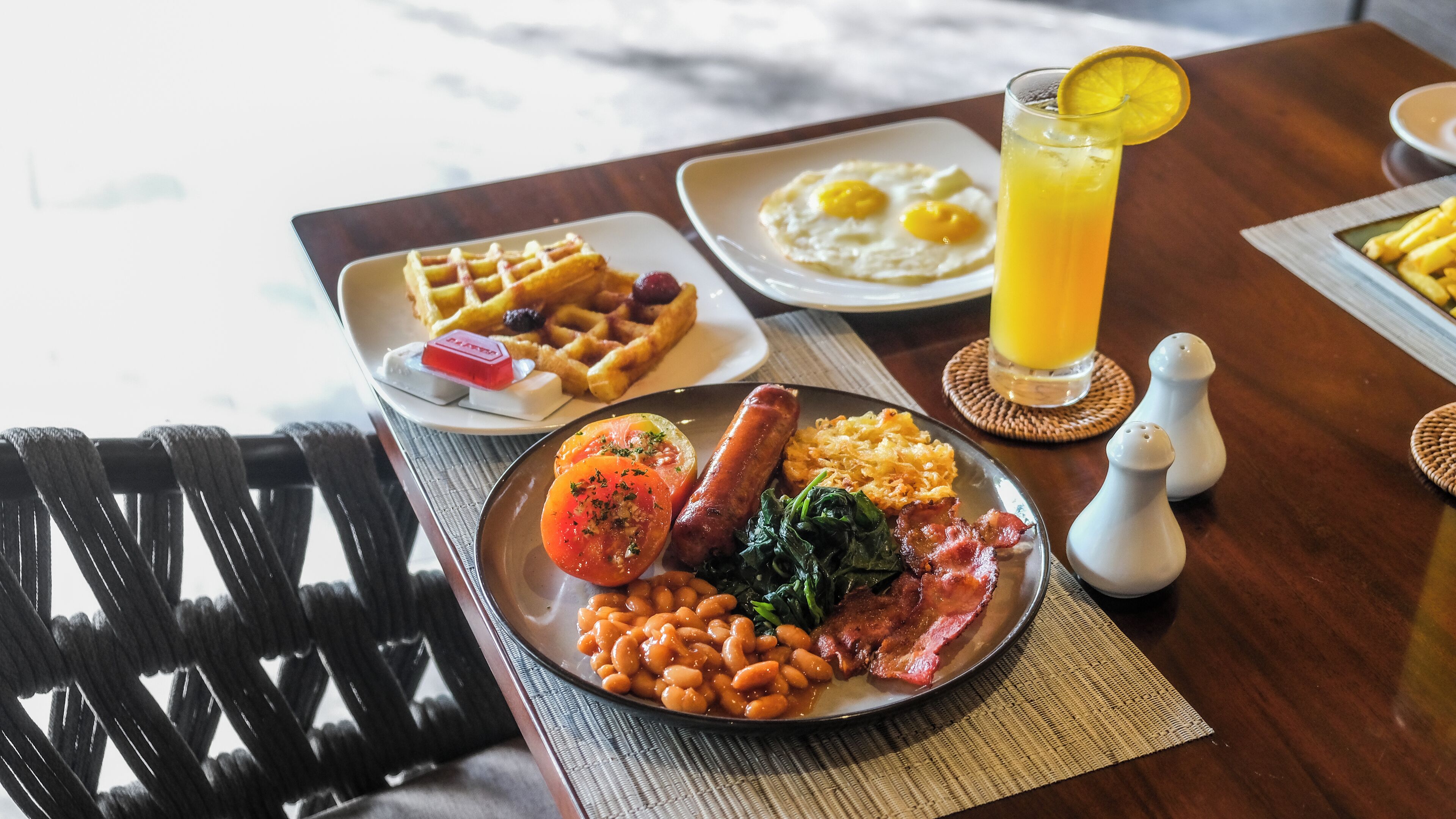 Prato de café da manhã com ovos, bacon, tomate, feijão e vegetais.