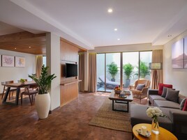 A modern living room with a flat-screen TV, a dining area with a wooden table, and a seating area with a sofa and armchairs.