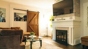 A living room with a fireplace, a TV mounted above it, and a sliding barn door.