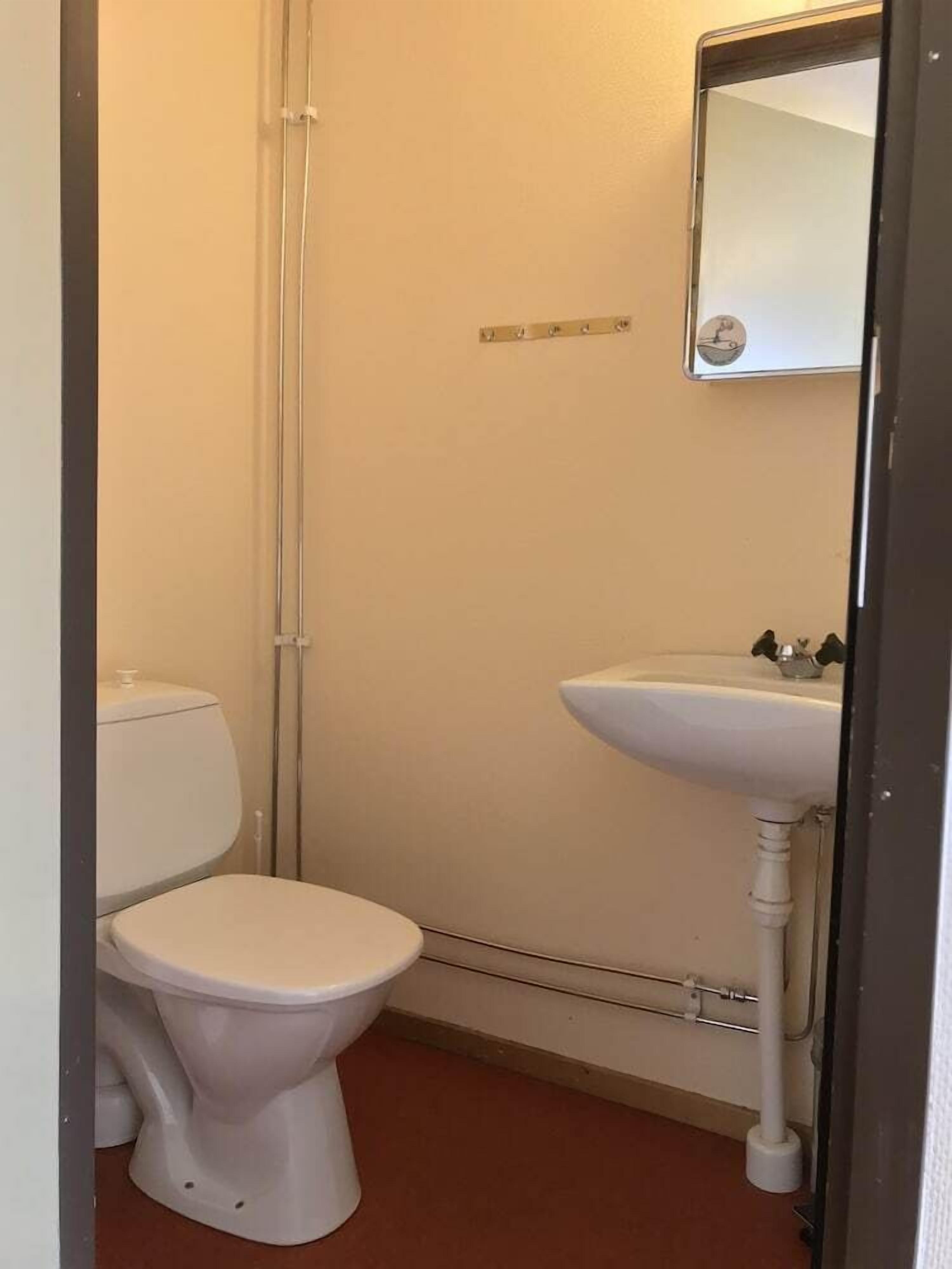 Un baño pequeño con inodoro, lavamanos y espejo.
