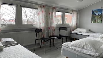 Ett rum med två sängar, en stol, ett bord och ett element.