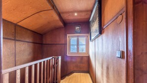 Ein Innenbereich mit Holzboden und Holzwand, eine Holztreppe, ein Fenster mit Bergblick und eine Tür mit Lichtschalter.