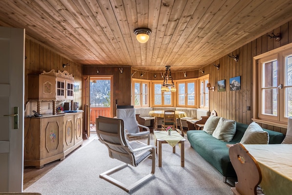 Un intérieur en bois comprenant une table à manger, des chaises, un canapé et un coin cuisine.