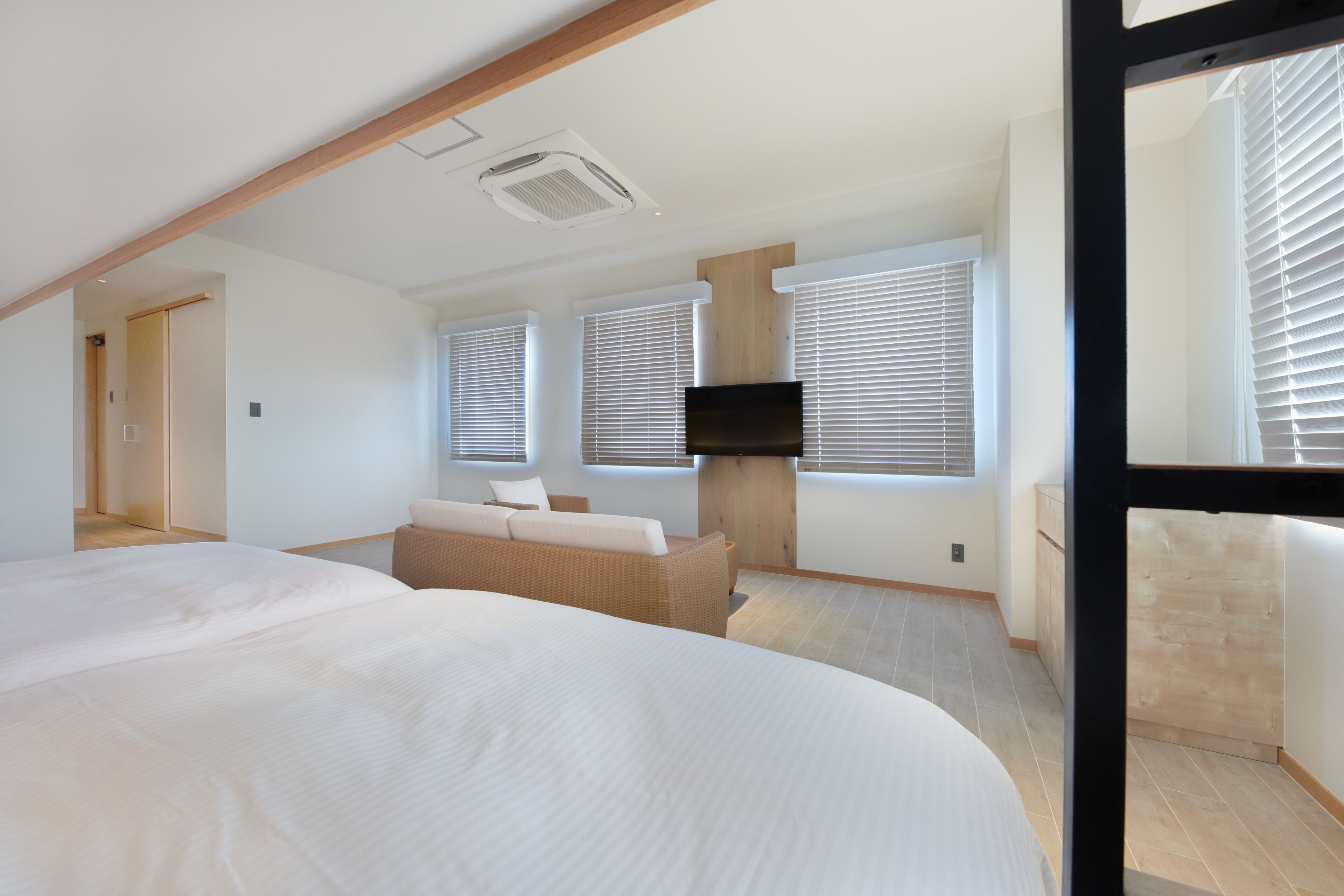 Ein modernes Schlafzimmer mit einem großen Bett, einer Couch und einem an der Wand befestigten Fernseher.