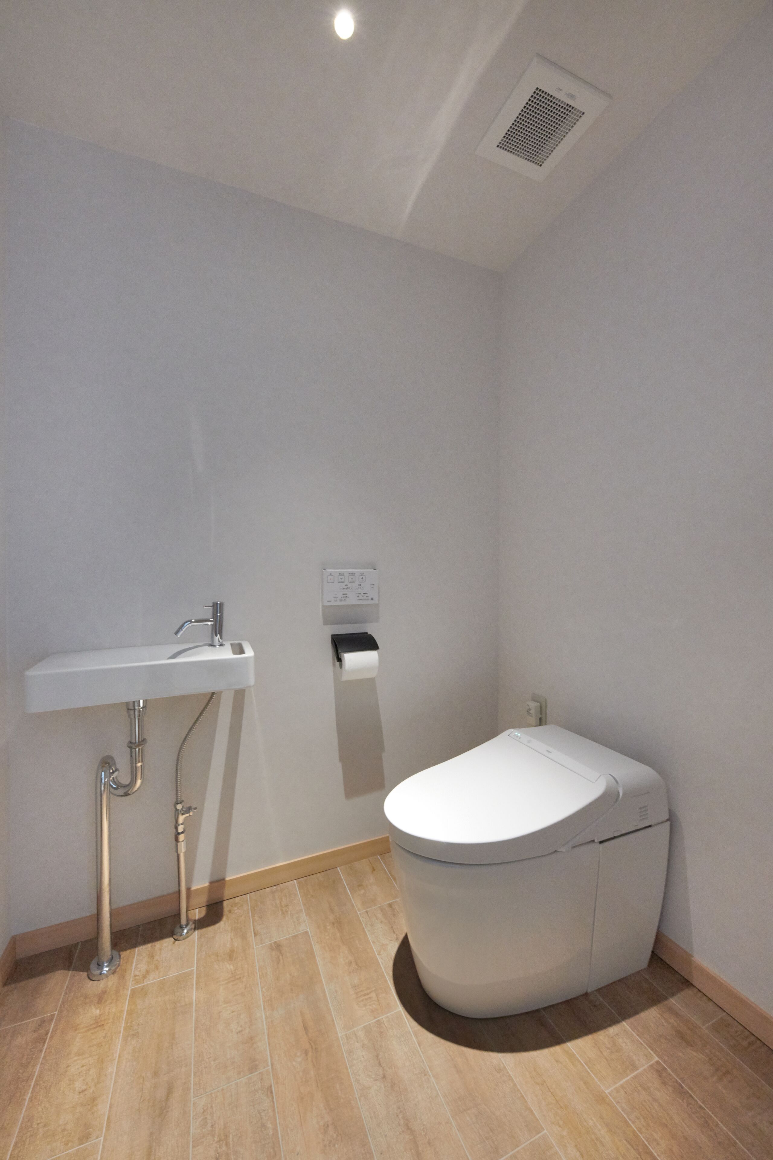 Une petite salle de bain moderne avec des toilettes blanches, un lavabo et une pomme de douche.