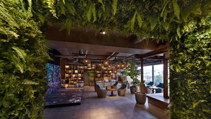 A modern interior with a large bookshelf, seating areas, and indoor plants. - THIRD Ishigaki (Ishigaki)