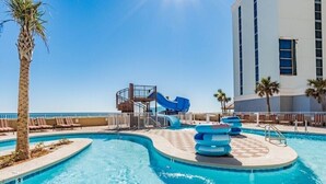 Ein Poolbereich mit einer blauen Rutsche, Liegestühlen und Palmen.