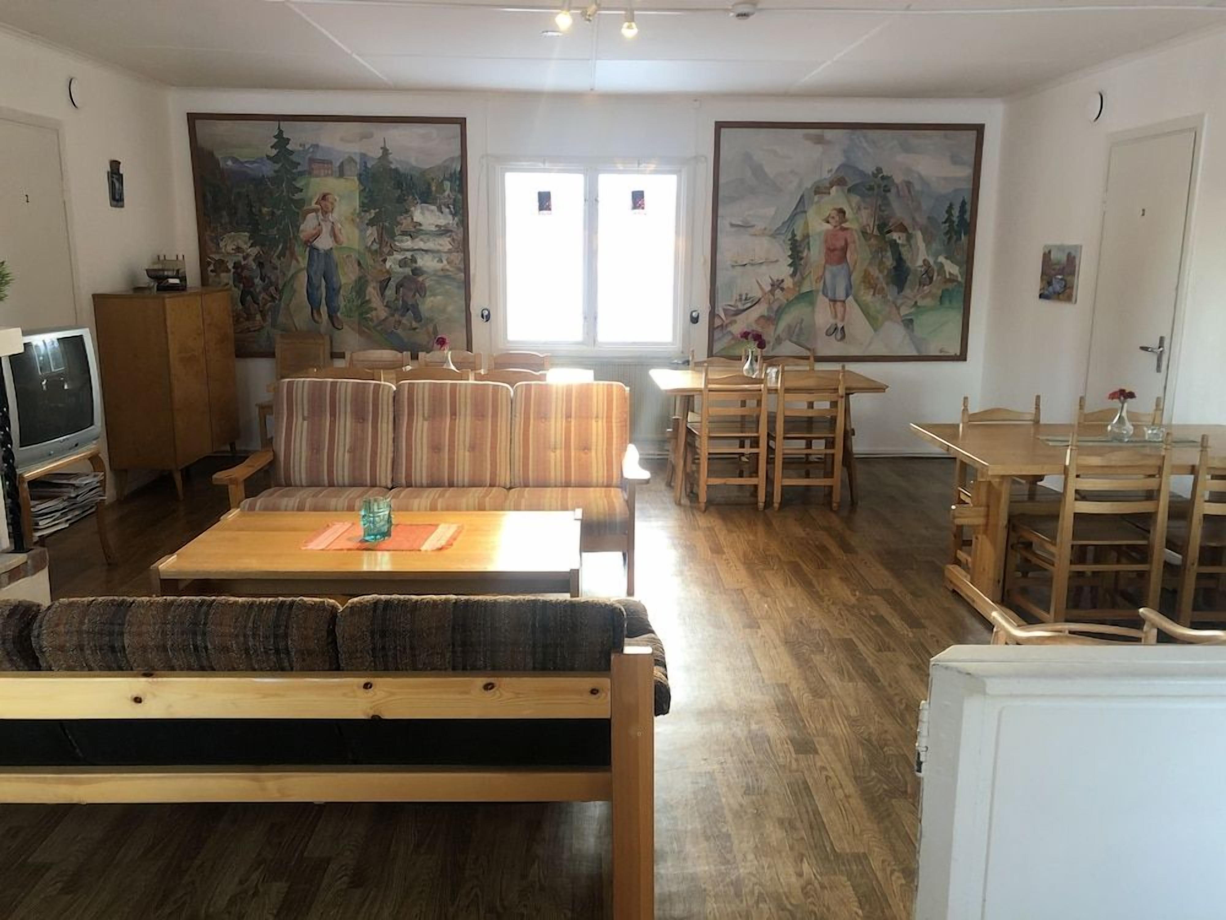 A living room with a sofa, a coffee table, a TV, and paintings on the walls.