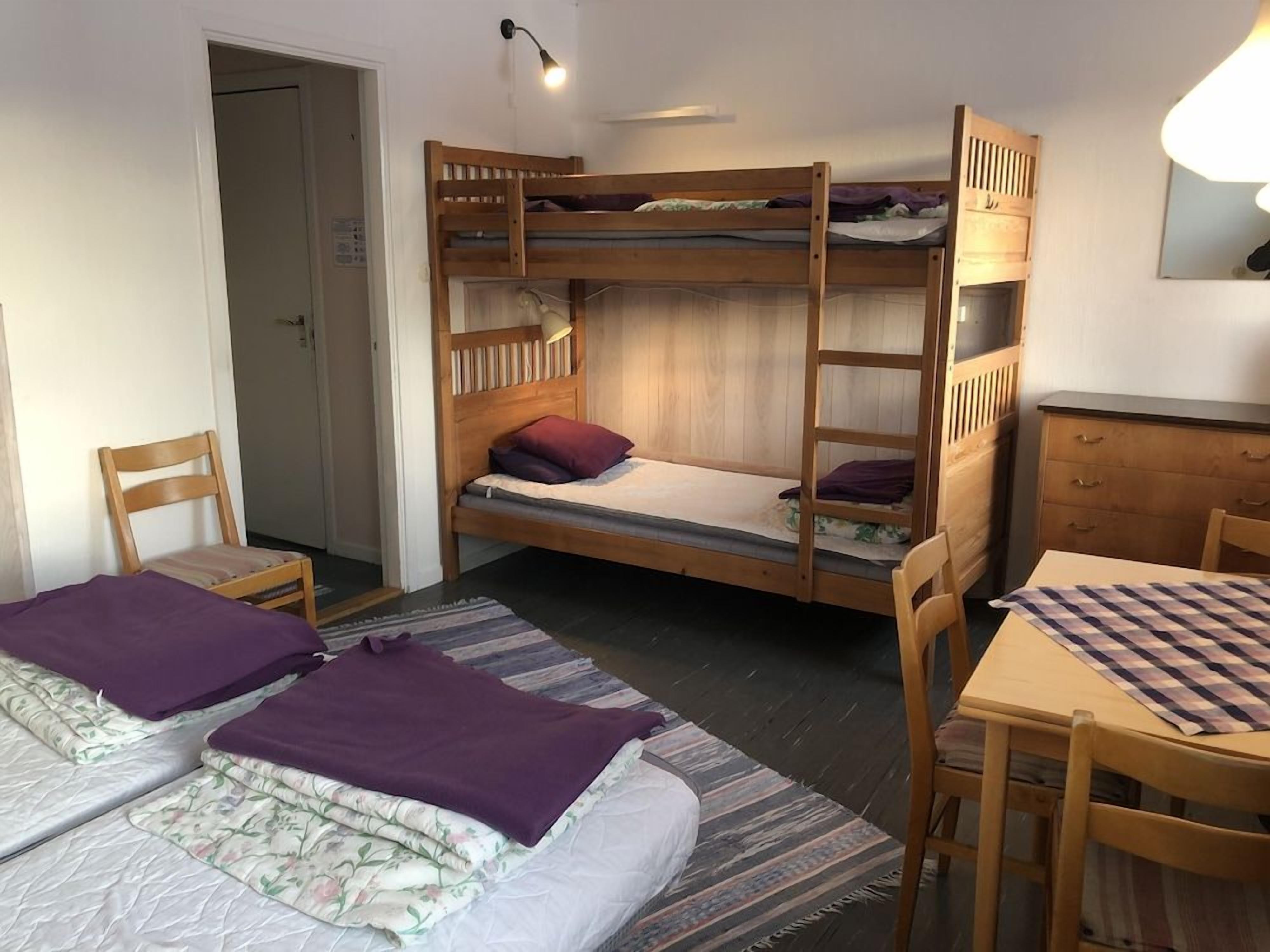 A dormitory room with bunk beds, a desk, a chair, and a small table.