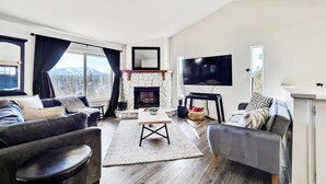 A modern living room with a fireplace, a flat-screen TV, and a view of mountains through large windows. - Luxe Private Truckee Getaway 20 Mins To Lake Tahoe (Truckee)