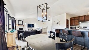 A modern kitchen with a central island, a dining area with a round table, and a bar area with stools. - Luxe Private Truckee Getaway 20 Mins To Lake Tahoe (Truckee)