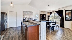 A modern kitchen with a central island, wooden cabinets, and a dining area with a table and chairs. - Luxe Private Truckee Getaway 20 Mins To Lake Tahoe (Truckee)