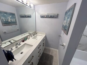 A bathroom with two sinks, a large mirror, and artwork on the walls. - Oasis on the Isle - Destin (Destin)
