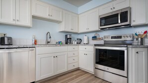 A kitchen with white cabinets, a microwave, a coffee maker, and an oven. - Bright and Delightful Renovation, Single Level, Fenced Backyard, 3 Blocks to MAX, 25 Min to Portland (Hillsboro)
