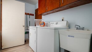A laundry area with a washing machine, a dryer, and a sink. - Bright and Delightful Renovation, Single Level, Fenced Backyard, 3 Blocks to MAX, 25 Min to Portland (Hillsboro)