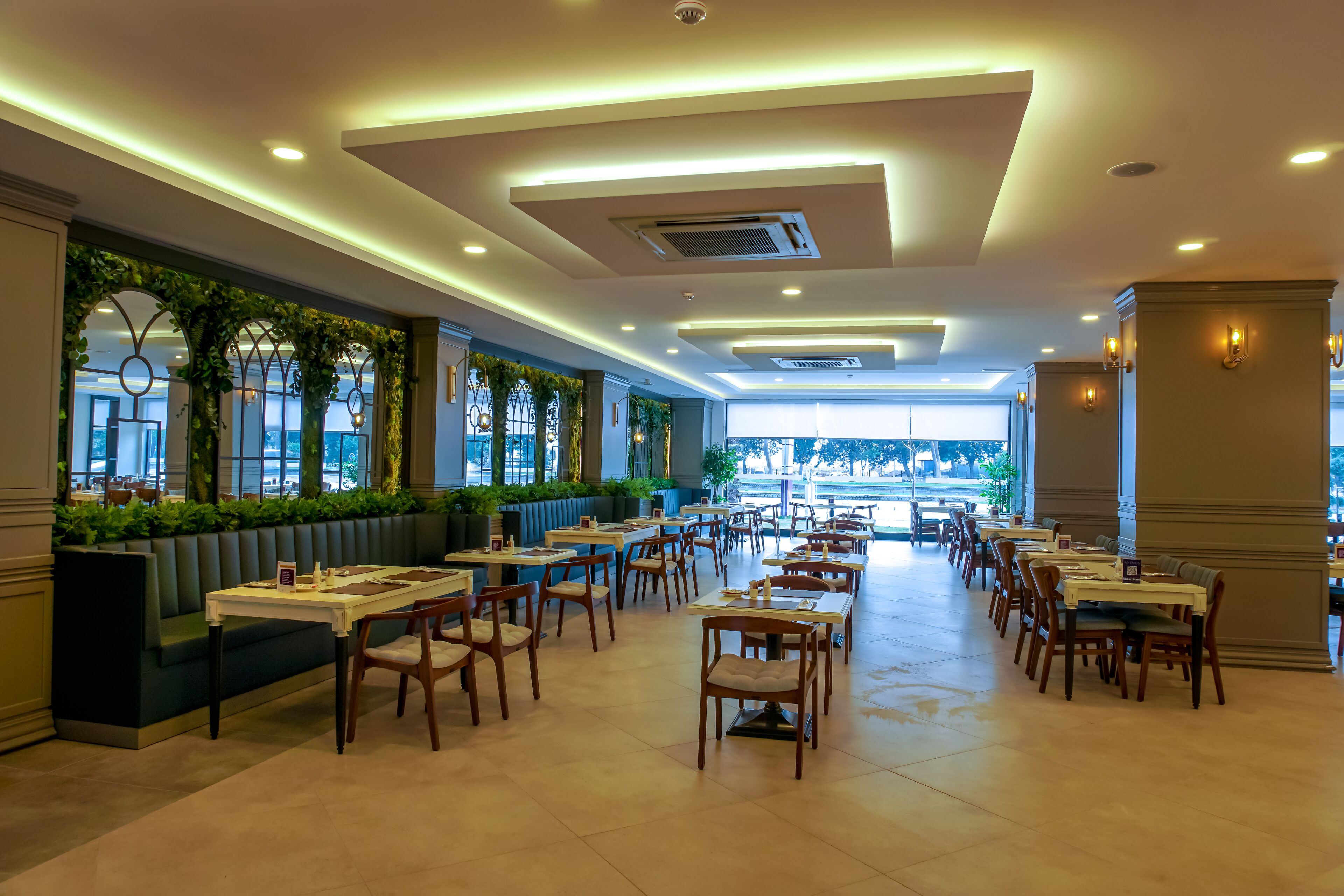 A spacious restaurant with high ceilings, recessed lighting, and a long counter with booths.
