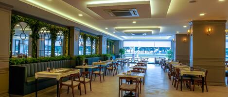 A spacious restaurant with high ceilings, recessed lighting, and a long counter with booths.