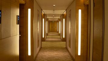 Un pasillo de hotel con paredes de madera, piso alfombrado y tiras verticales de luz iluminadas.