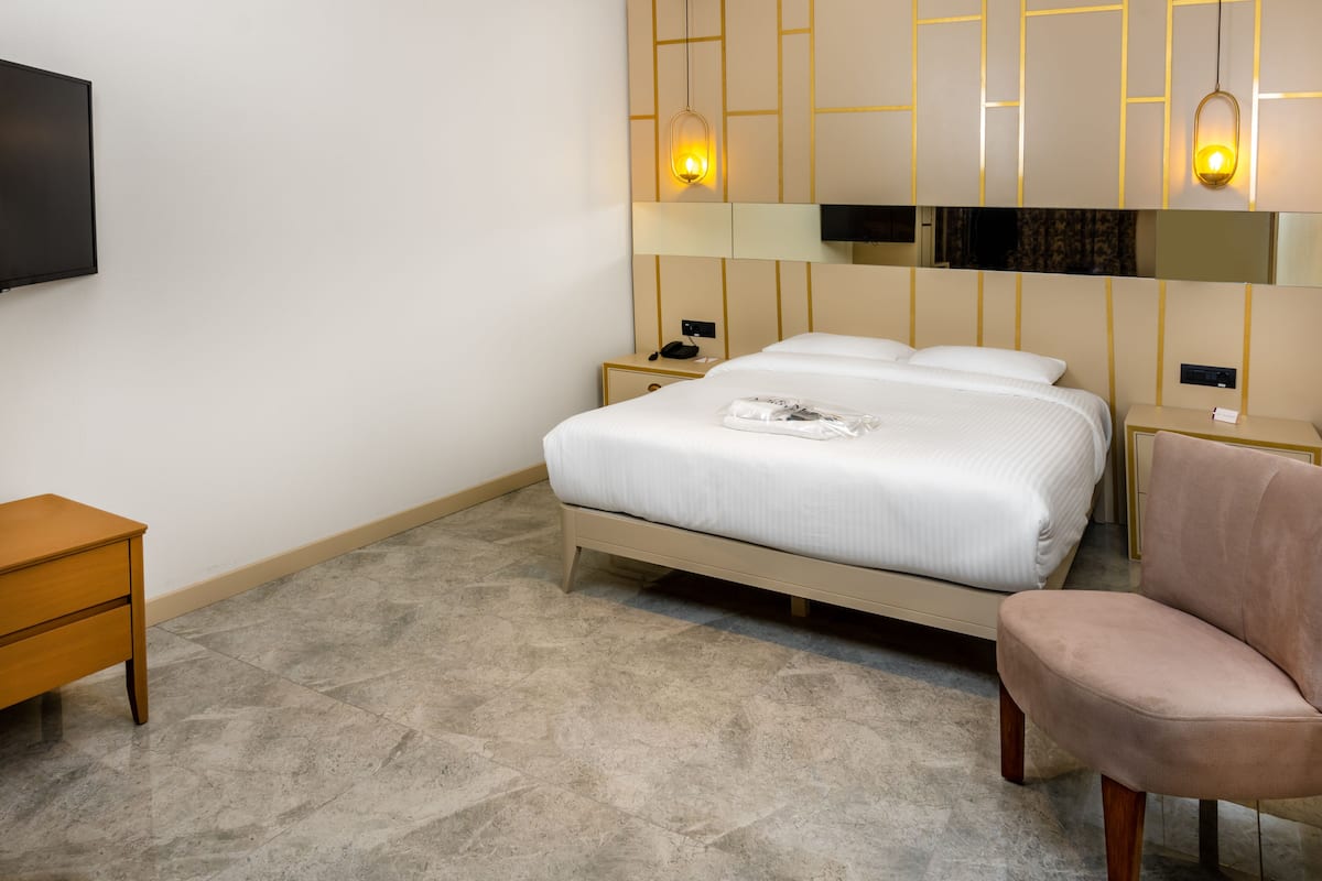 Una habitación de hotel con cama, mesitas de noche, una silla y televisor.