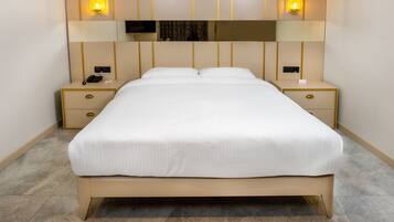 Cama bem arrumada em quarto de hotel com design moderno, incluindo cabeceira com iluminação integrada e pequena mesa de cabeceira com telefone e abajur.