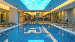 A modern indoor swimming pool with a ceiling light display, lounge chairs, and exercise equipment. - Anemon Kent Aydın Otel (Aydin)