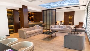 A modern living room with a large glass ceiling, a sofa set, a coffee table, and a seating area with chairs. - Anemon Kent Aydın Otel (Aydin)
