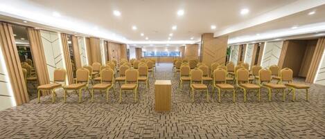A conference room with rows of chairs, a podium, and a patterned carpet.
