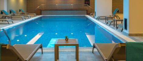 A swimming pool with lounge chairs and a table in the foreground.