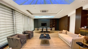 A modern hotel lobby with a large seating area, a flat-screen TV, and a ceiling with a tree projection. - Anemon Kent Aydın Otel (Aydin)