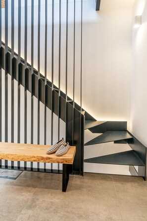 A modern staircase with a wooden bench and striped slippers placed on it.