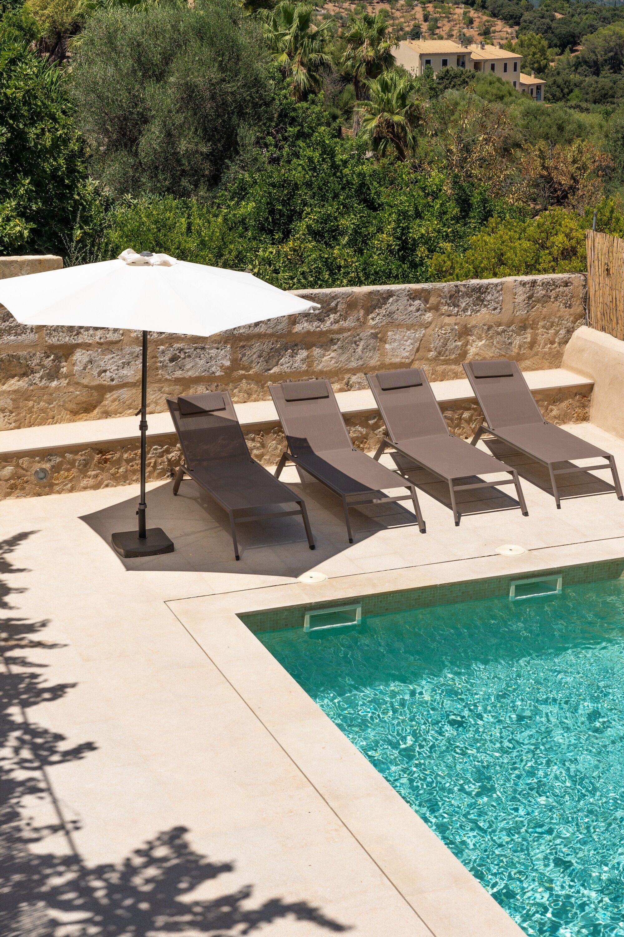 Zona de piscina con sillas de descanso y una sombrilla.