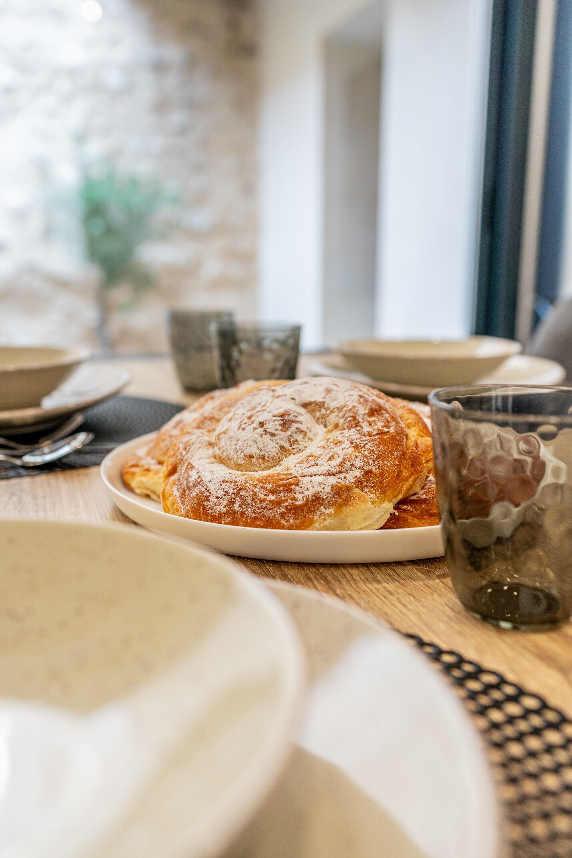 A table with a plate of food, a glass, and a cup.