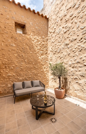 A courtyard with a sofa, a round table, and a potted plant.