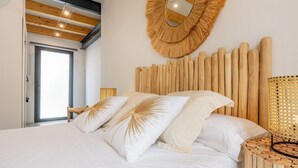 Una camera da letto con un letto, una testiera in legno, uno specchio rotondo e un arazzo decorativo a parete.