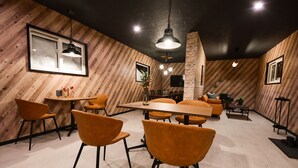 A modern dining area with wooden walls, a central table, and orange chairs. - Rusutsu Grand Cabin (Kimobetsu)