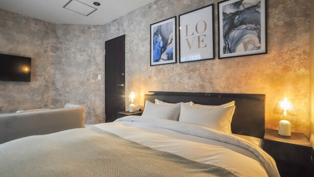 A modern bedroom with a large bed, two bedside tables with lamps, and three framed artworks on the wall. - Rusutsu Grand Cabin (Kimobetsu)