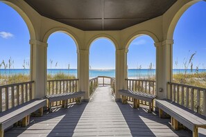 A wooden boardwalk leading to a beach with a clear view of the ocean.