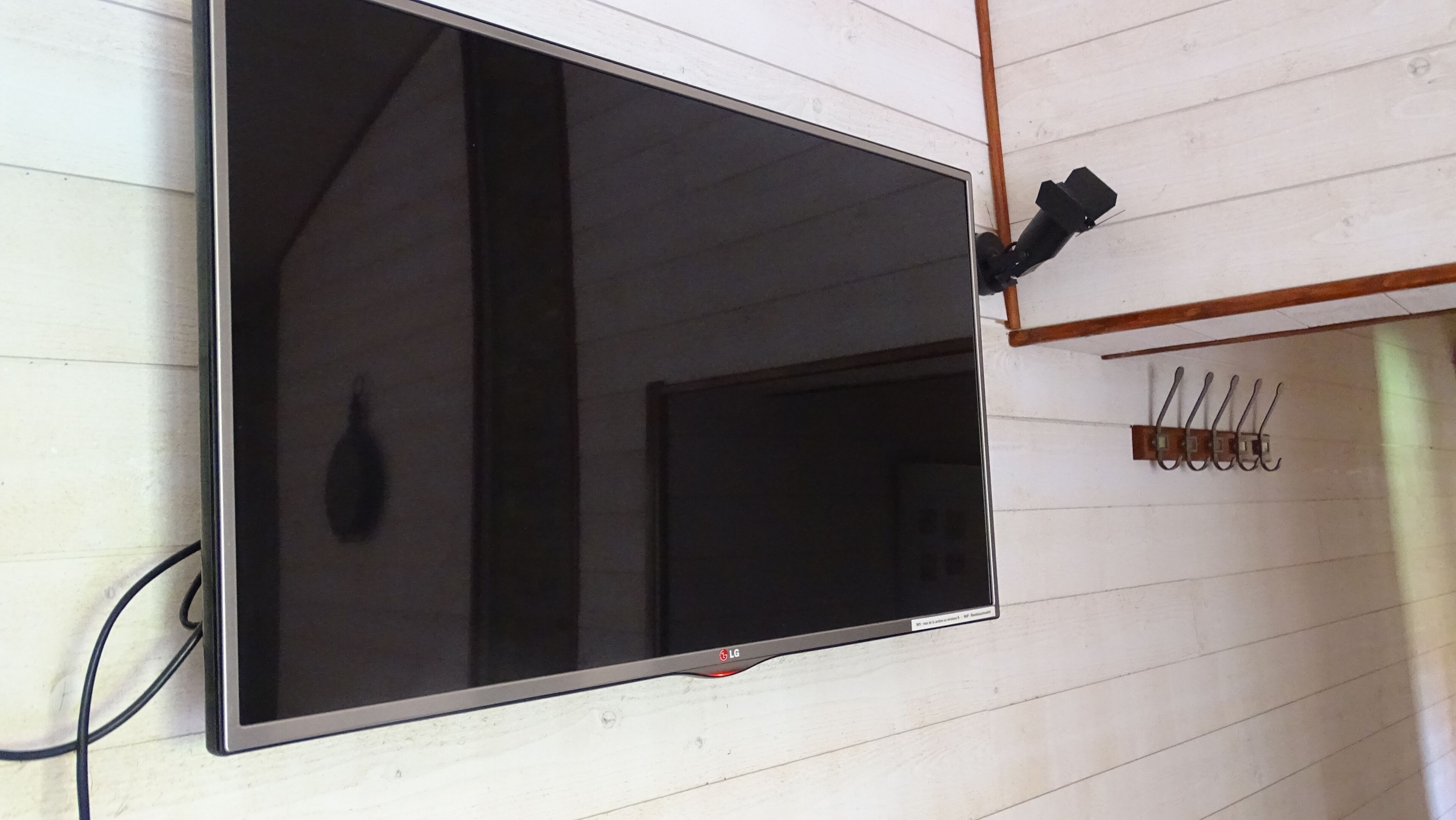 Een flatscreen televisie bevestigd aan een muur, met een kabel aangesloten.