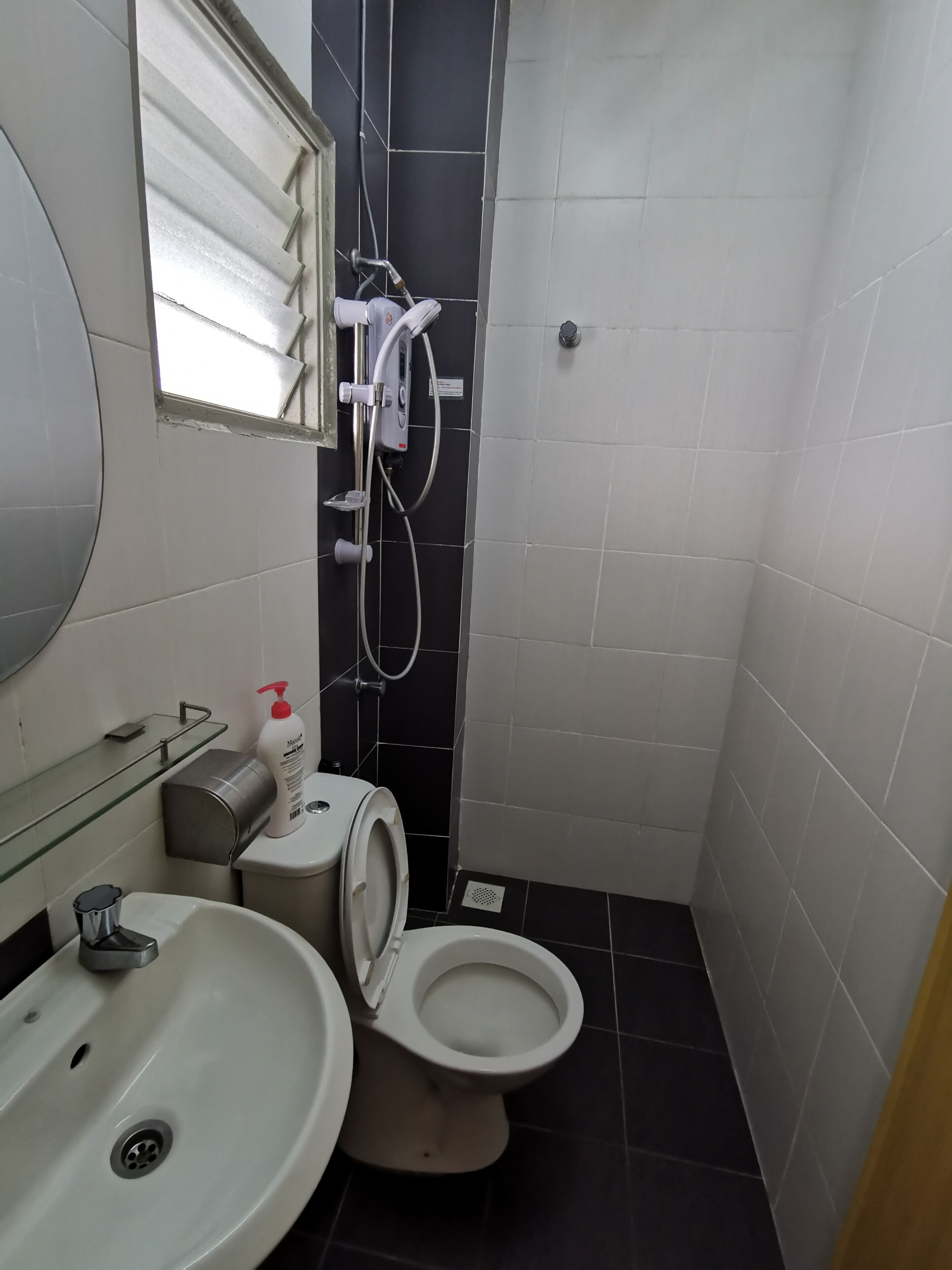 A small bathroom with a toilet, sink, and shower.