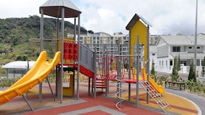 Ein Spielplatz mit Rutschen, Klettergerüsten und einem überdachten Bereich.